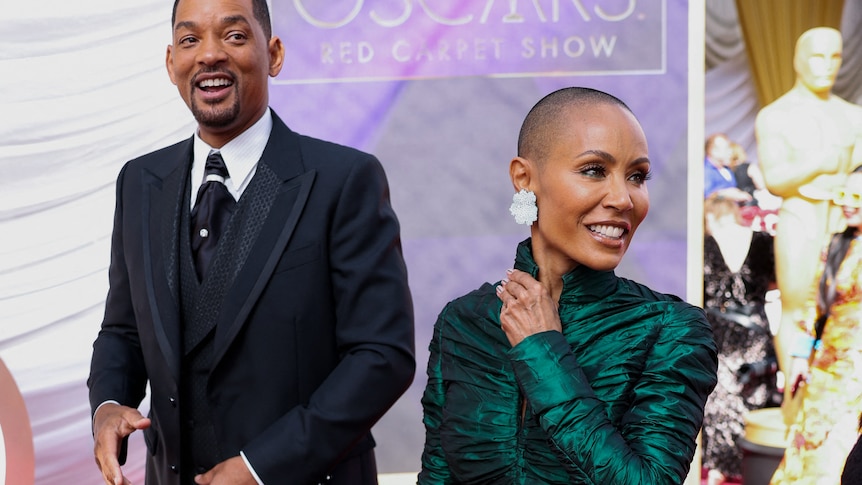 Will Smith and Jada Pinkett Smith pose on the red carpet during the Oscars.