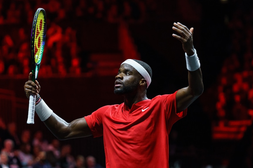 Frances Tiafoe of the US celebrates with his hands in the air, including a racquet in one
