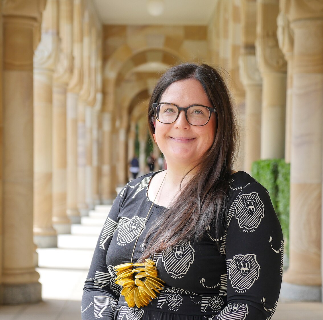 Uma foto profissional de Stacey Parker tirada entre arcos de arenito na Universidade de Sydney.