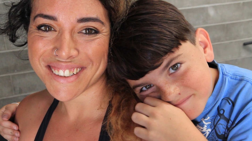 Close up on a smiling woman and a young boy who has his head on her shoulder and his arms around her.