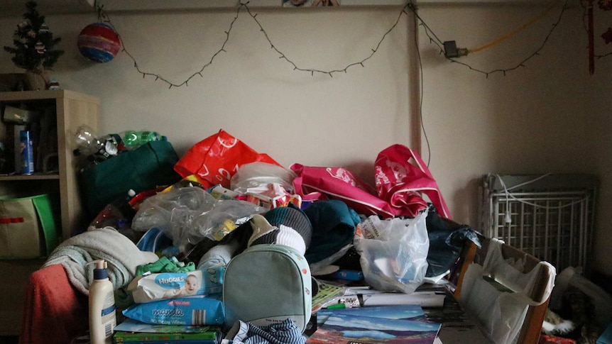 A table with lots of clutter and baby items.