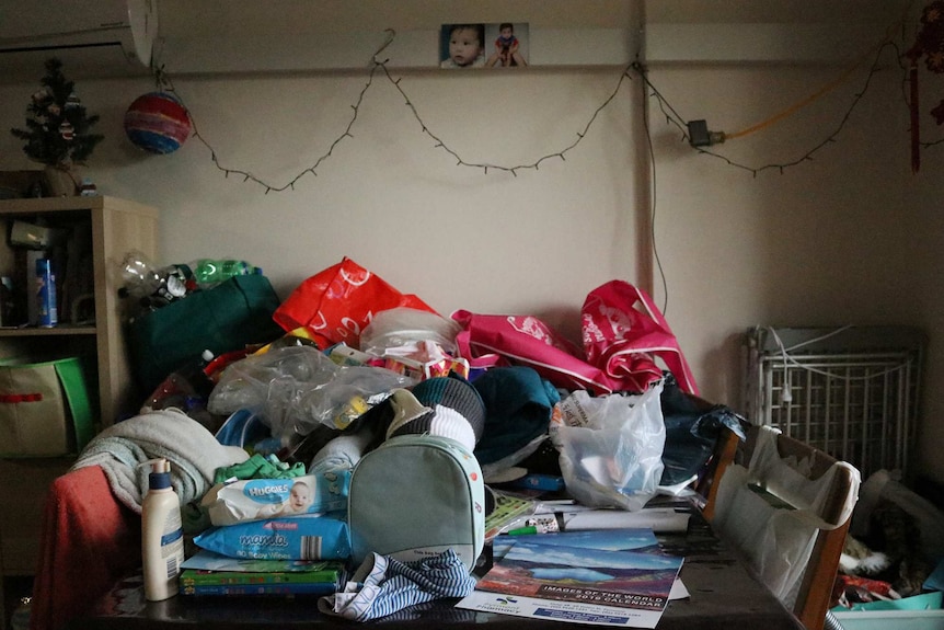 A table with lots of clutter and baby items.