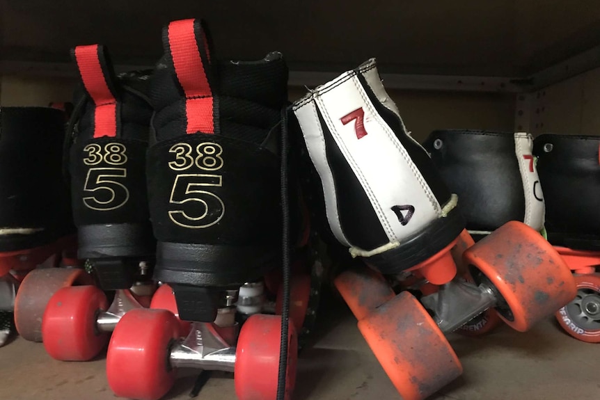 Close up photograph of two roller skates from behind. One pair is black and red, the other black and white