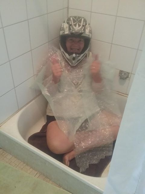 A person wearing a motorbike helmet in a shower.