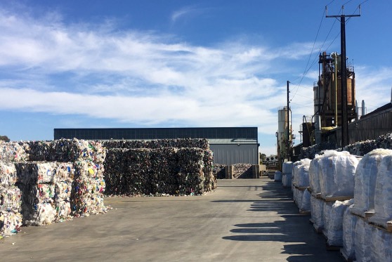 Compressed bundles of plastic sit in a concrete yard