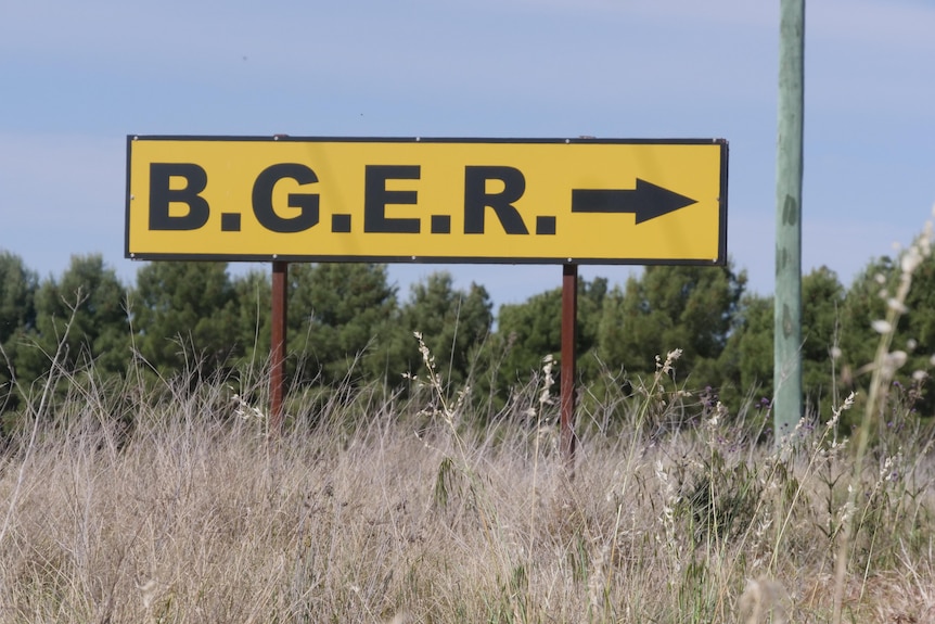 A yellow road sign with black letters spelling out BGER