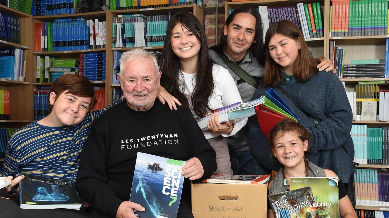 Les and a group of children holding books. 