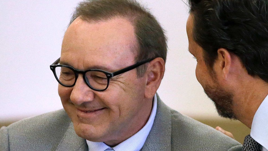 Kevin Spacey smiles as a man speaks to him.
