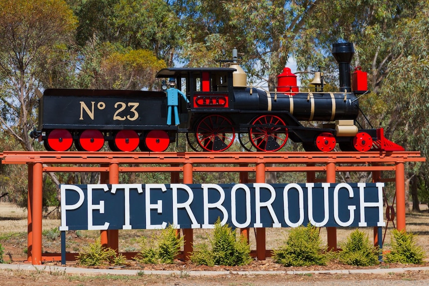A red sign reading "Peterborough" with a mini steam train on top of it.