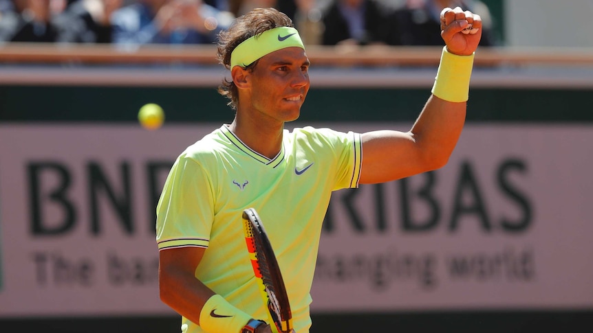 Rafael Nadal clenches his fist and smiles in a yellow t-shirt, and yellow sweat bands