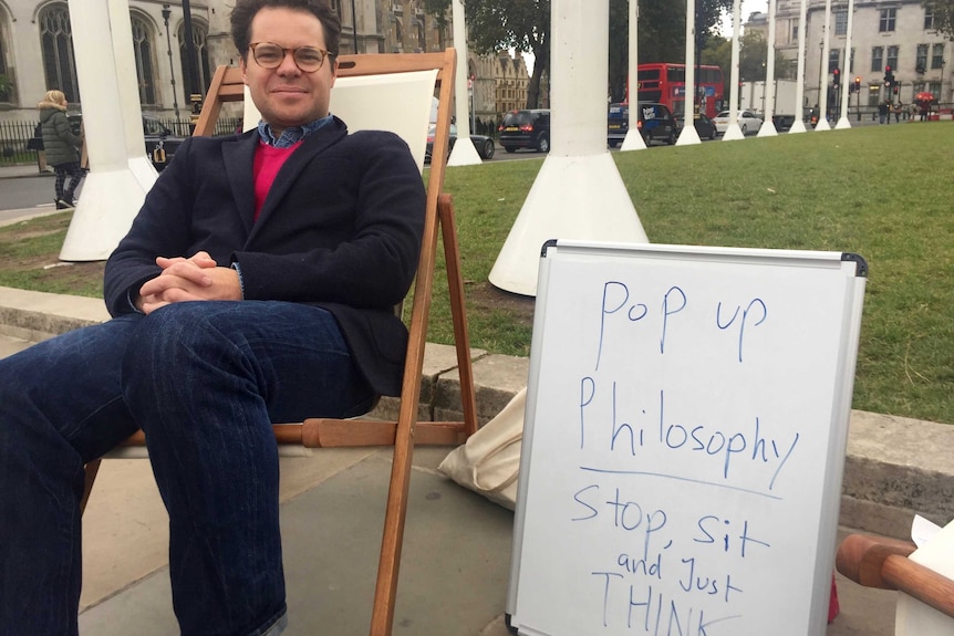Andre Spicer sitting on a pop up philosophy chair in London