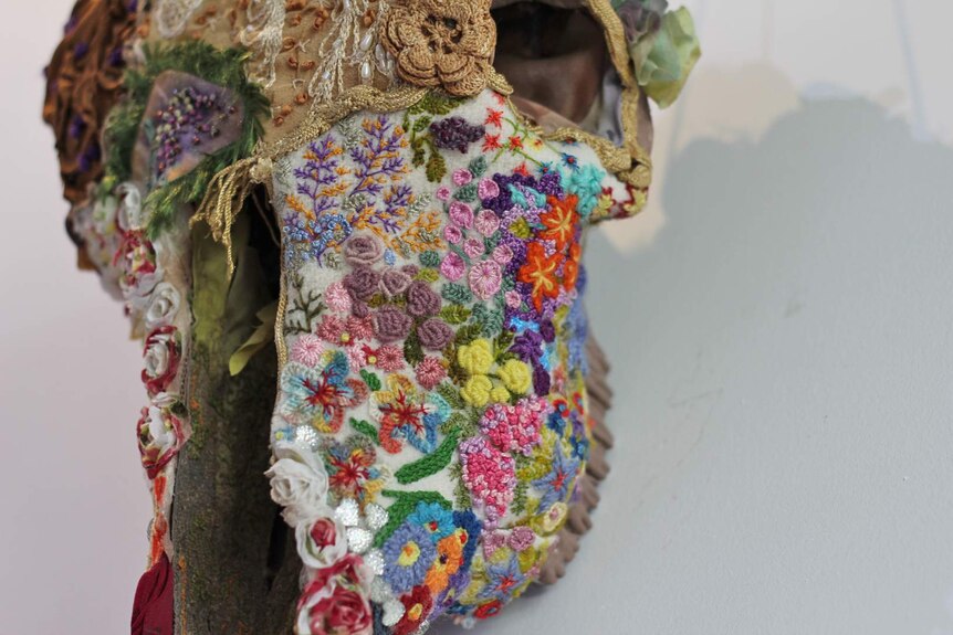 a cow skull decorated with intricate wool embroidery of flowers and lace