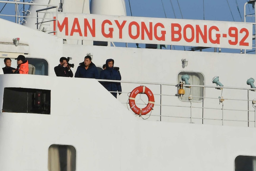 A few passengers stand on a ferry with signage reading 'Mangyongbong-92'.