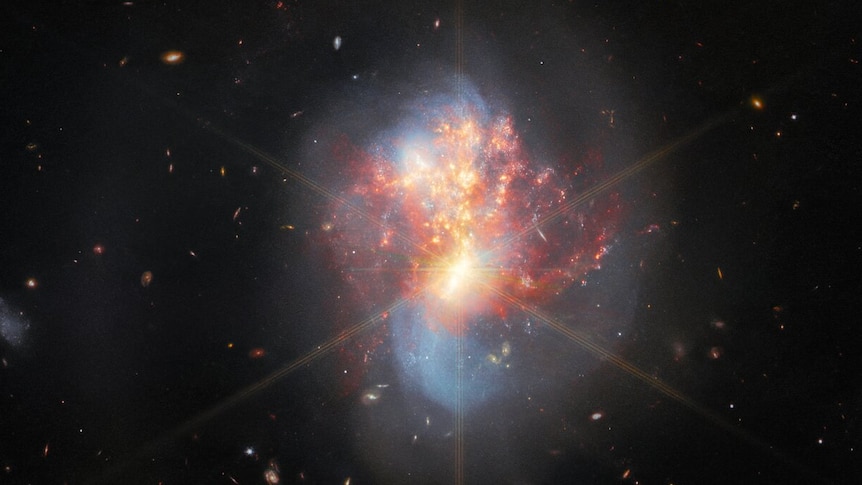 The two galaxies swirl into a single chaotic object in the centre. 