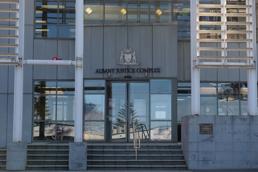 A grey building with the large sign "Albany Justice Complex"