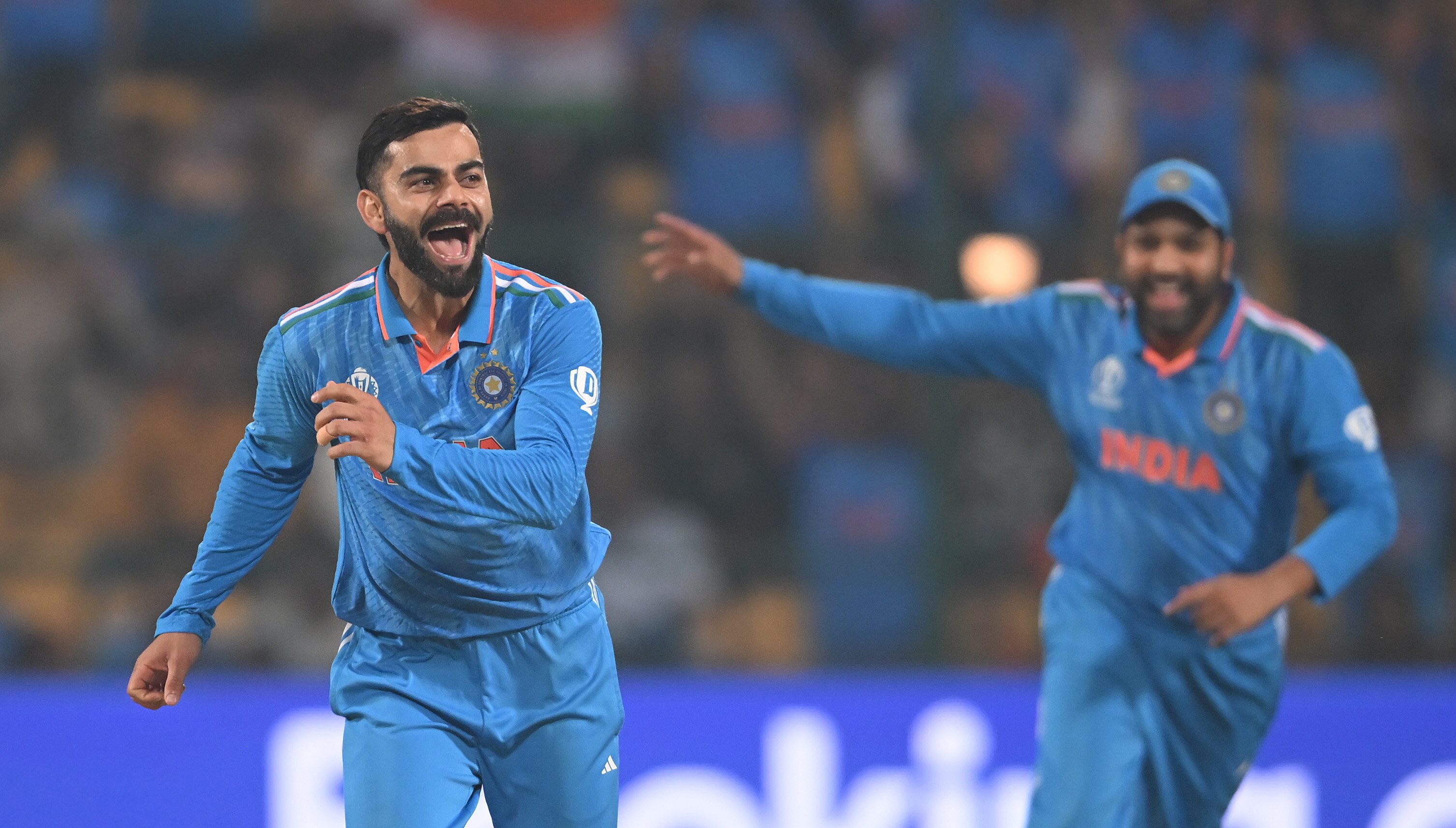 Virat Kohli runs off and smiles after taking a wicket