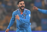 Virat Kohli runs off and smiles after taking a wicket