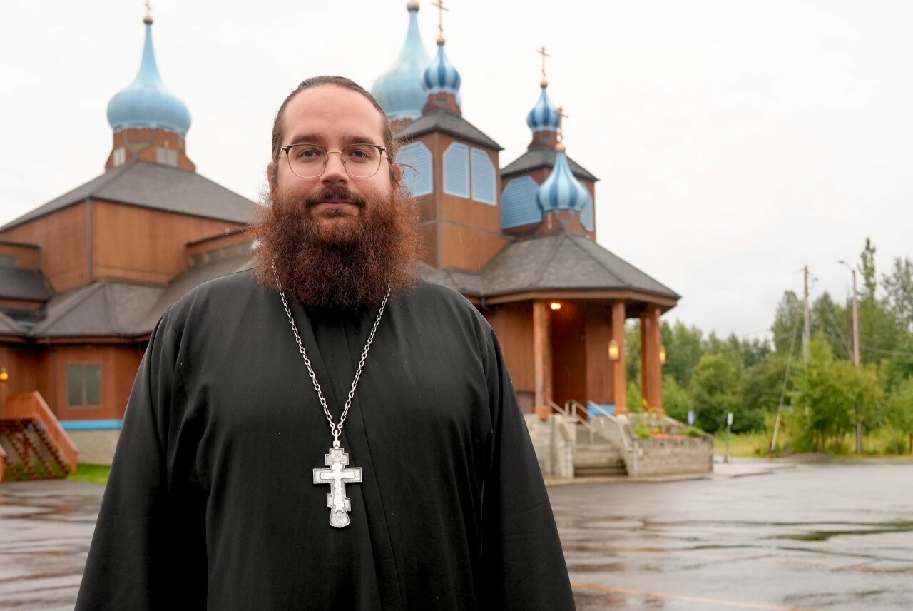 A man in religious clothing looks at the camera.