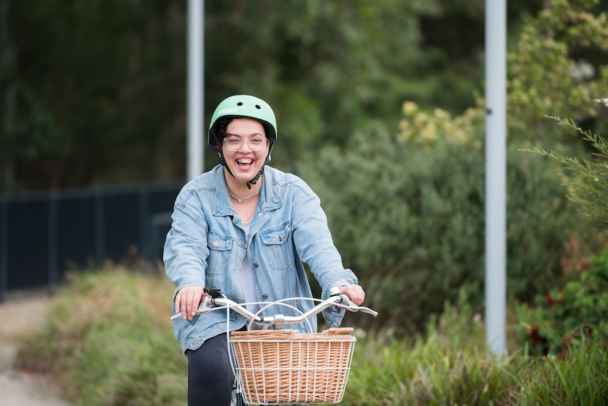Ella is seen laughing as she rides an old fashioned Dutch-style bicycle in a park, wearing a mint helmet.