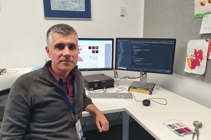 Jame Trauer sits on a chair in front of his computer.