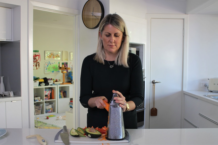 woman in kitchen shredding carrot