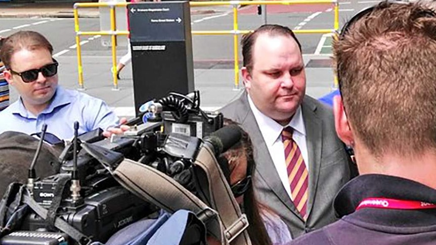 Scott Driscoll arrives at court as a throng of media surround him.