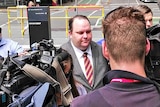 Scott Driscoll arrives at court as a throng of media surround him.