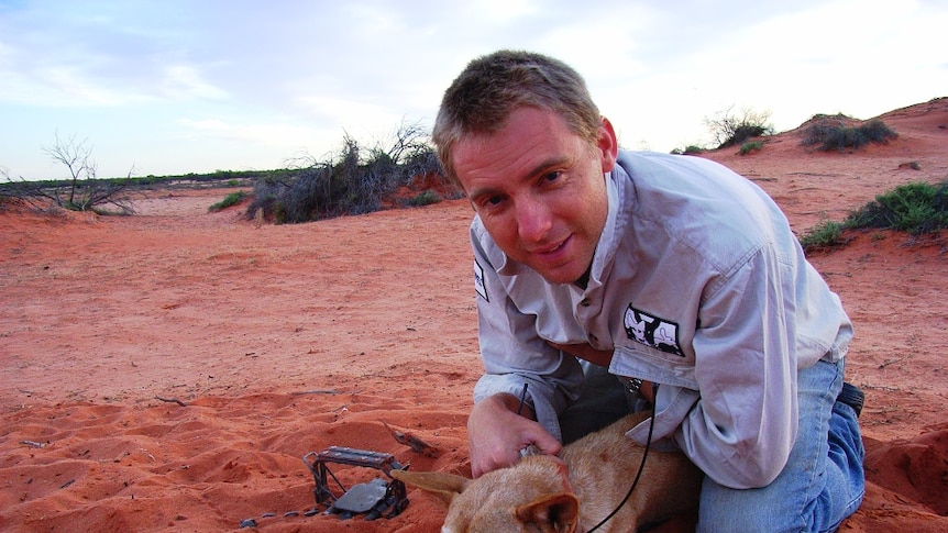 Ben Allen sitting atop a dingo in the desert in far western Queensland