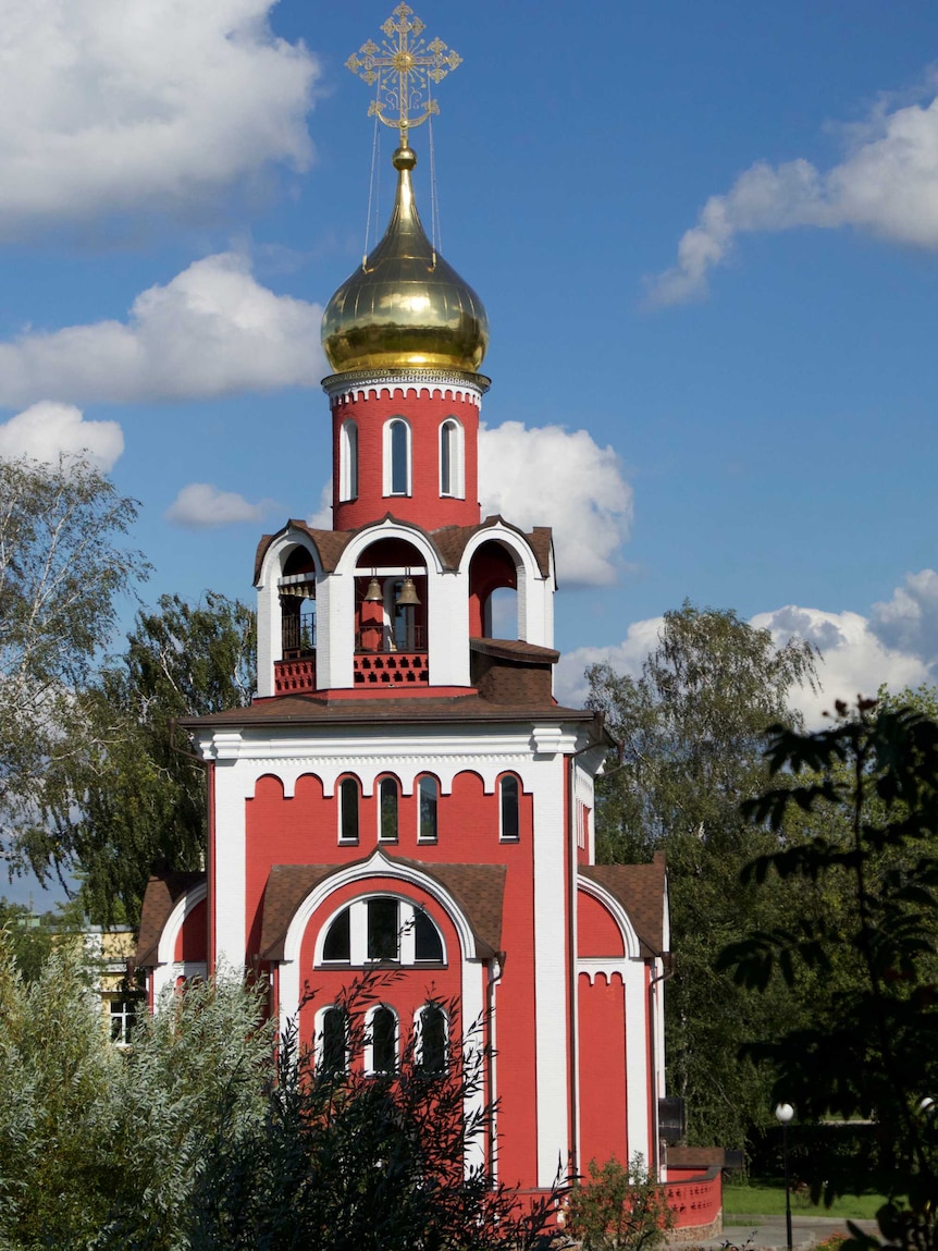 A red traditional Russian chapel with gold spire.