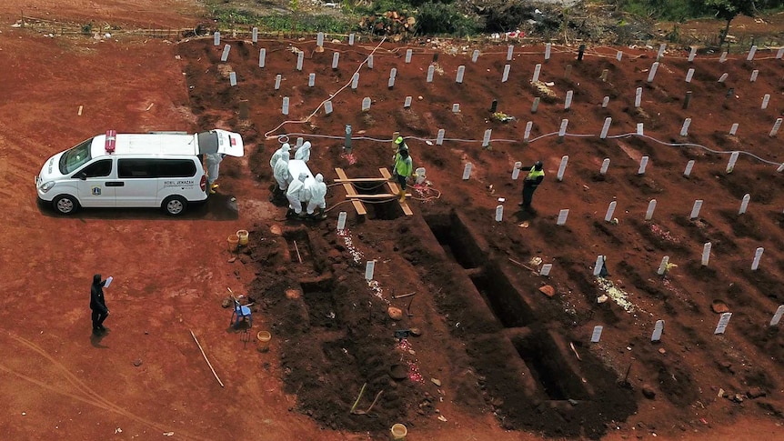 A group of people wearing protective clothes burying a coffin