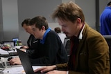 Three men working away at their computers.