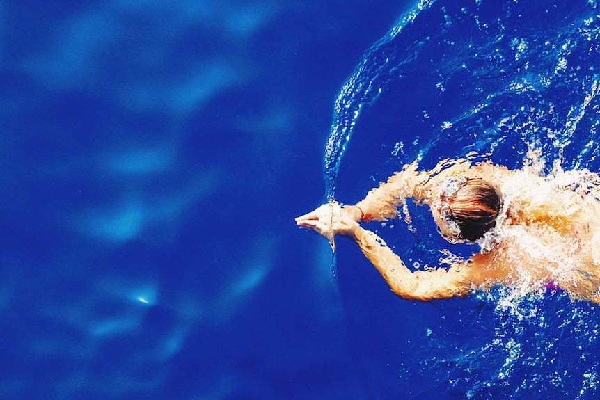 Aerial view of a swimmer in a deep blue body of water