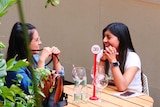 Two women smile while sitting at a restaurant table.