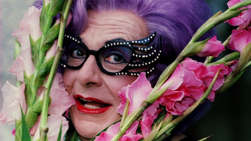Australian star Dame Edna Everage with a trademark bunch of gladioli flowers.