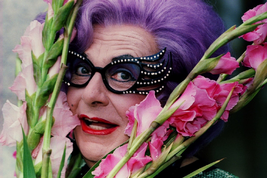 Australian star Dame Edna Everage with a trademark bunch of gladioli flowers.