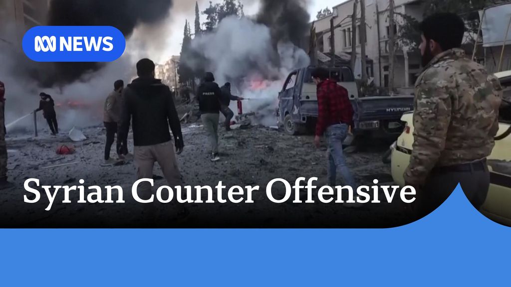 Syrian Counter Offensive: Men stand around a street filled with debris and destroyed vehicles.