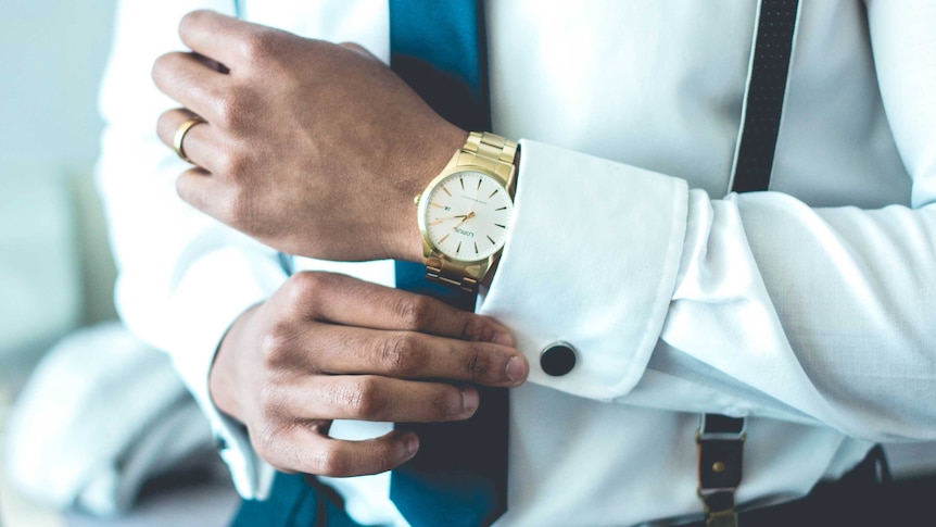 A man adjusts his cufflinks with a fancy watch