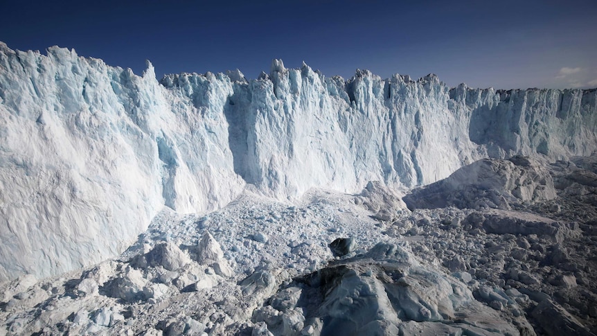 A large white ice sheet is seen against a blue sky.