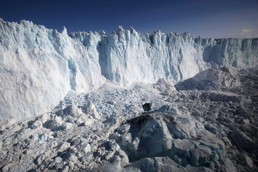 A large white ice sheet is seen against a blue sky.