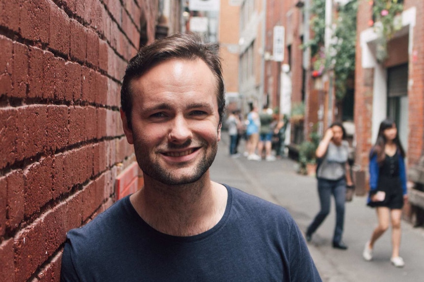 A man standing in an alley next to a brick wall