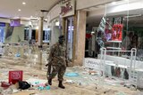 A soldier walks through a damaged mall with debris littered across the fall.