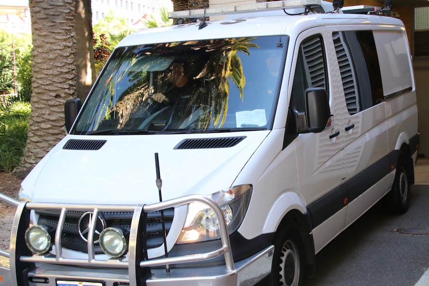 A white prison van in a driveway.