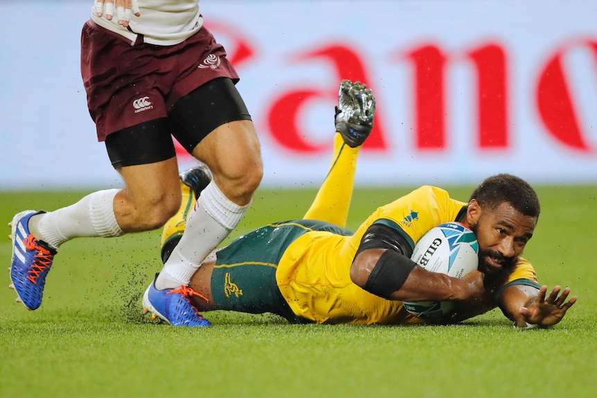 A Wallabies player slides on the ground as he scores a try against Georgia at the Rugby World Cup.