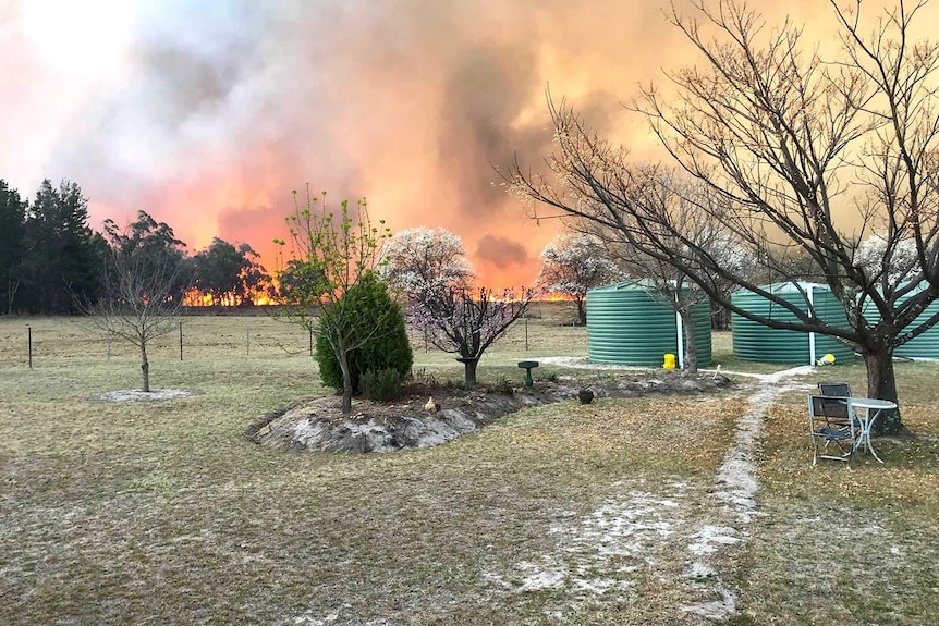 Bushfire burning on the horizon near a country property