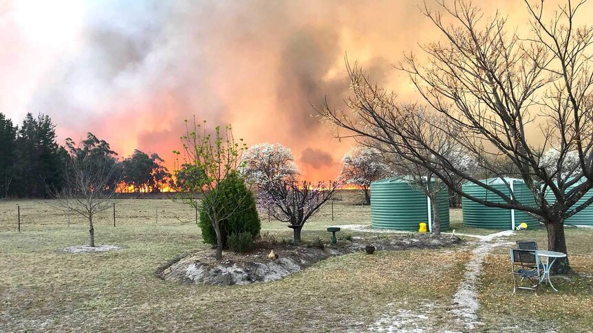 Bushfire burning on the horizon near a country property.