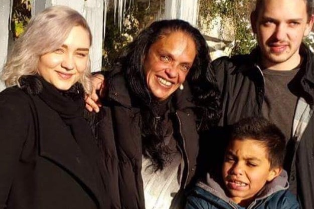 Catherine smiles with her three children, her older son's arm around her.