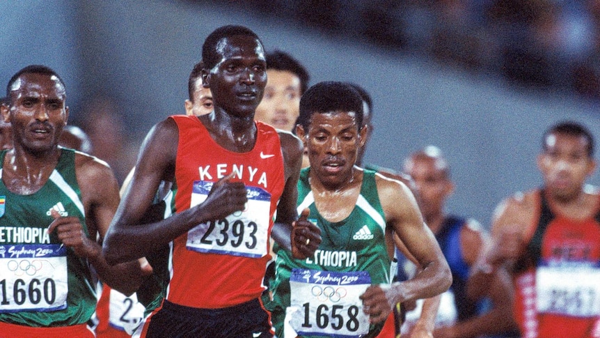 Haile Gebrselassie runs with his head down in a group of people
