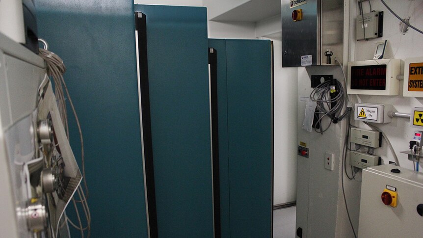 A side view of a thick, concertinaed, teal coloured concrete door.