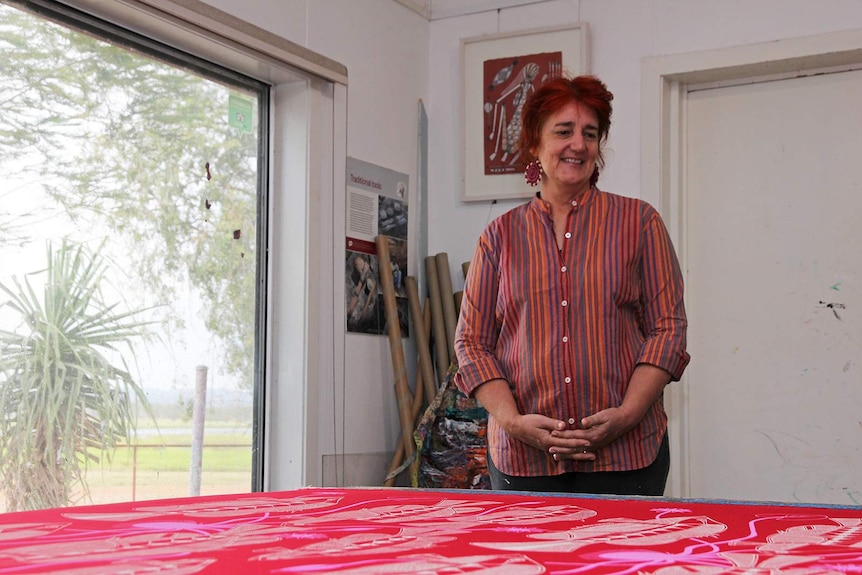 Injalak Arts manager Felicity Wright looks down on a freshly printed, vibrantly coloured print.