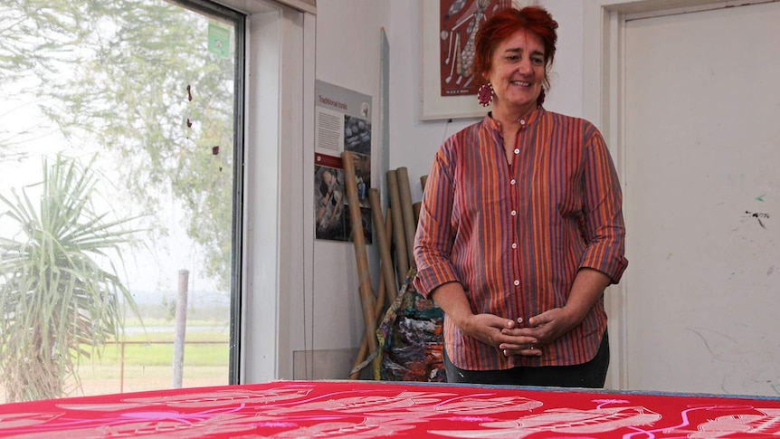 Injalak Arts manager Felicity Wright looks down on a freshly printed, vibrantly coloured print.